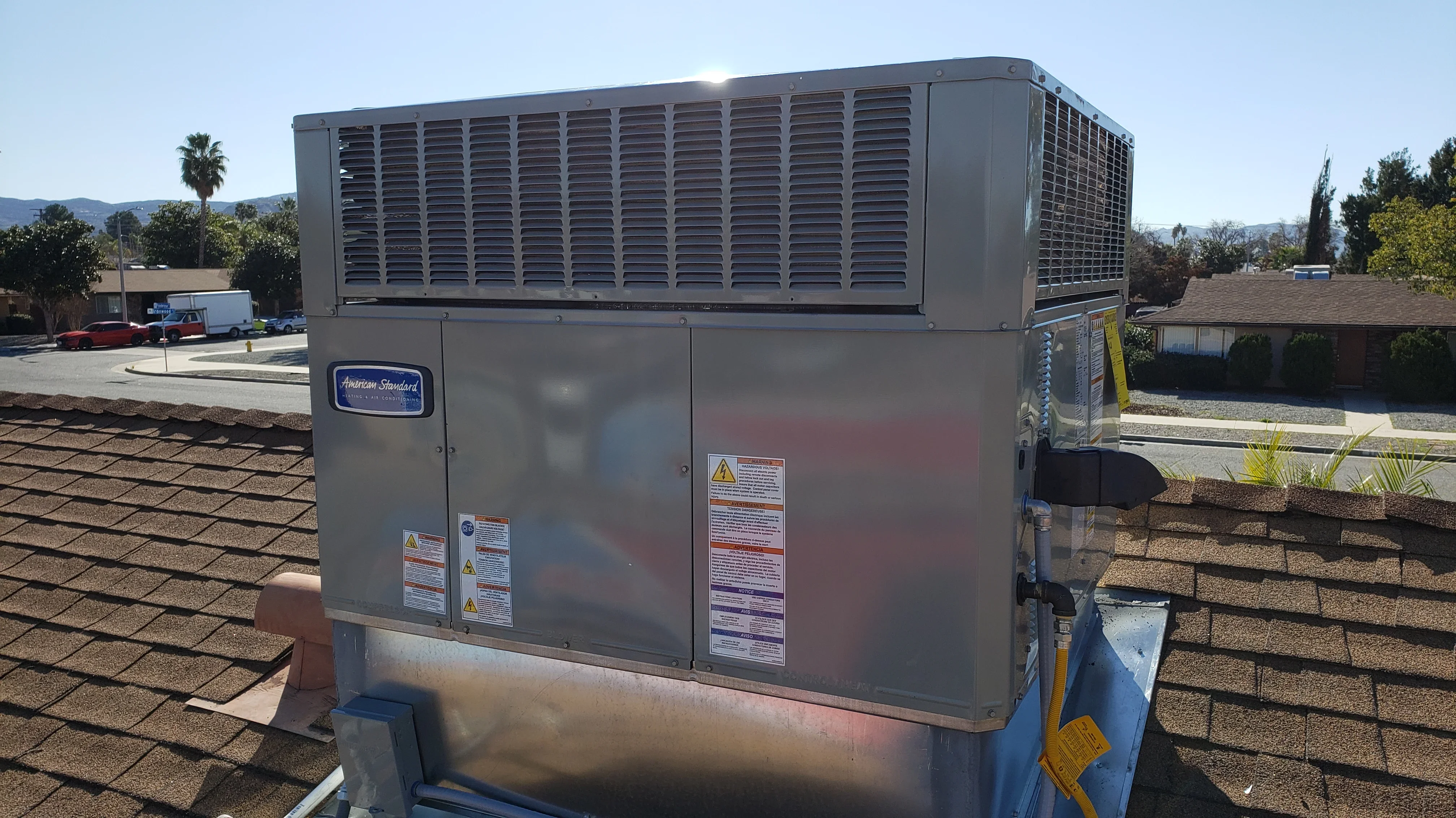 Commercial rooftop HVAC unit with dual condensers installed on shingled roof