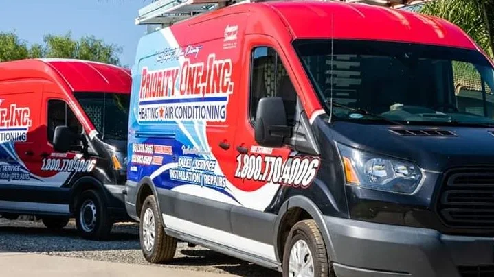 Red and white branded HVAC service vans parked in a row with company logo and phone number