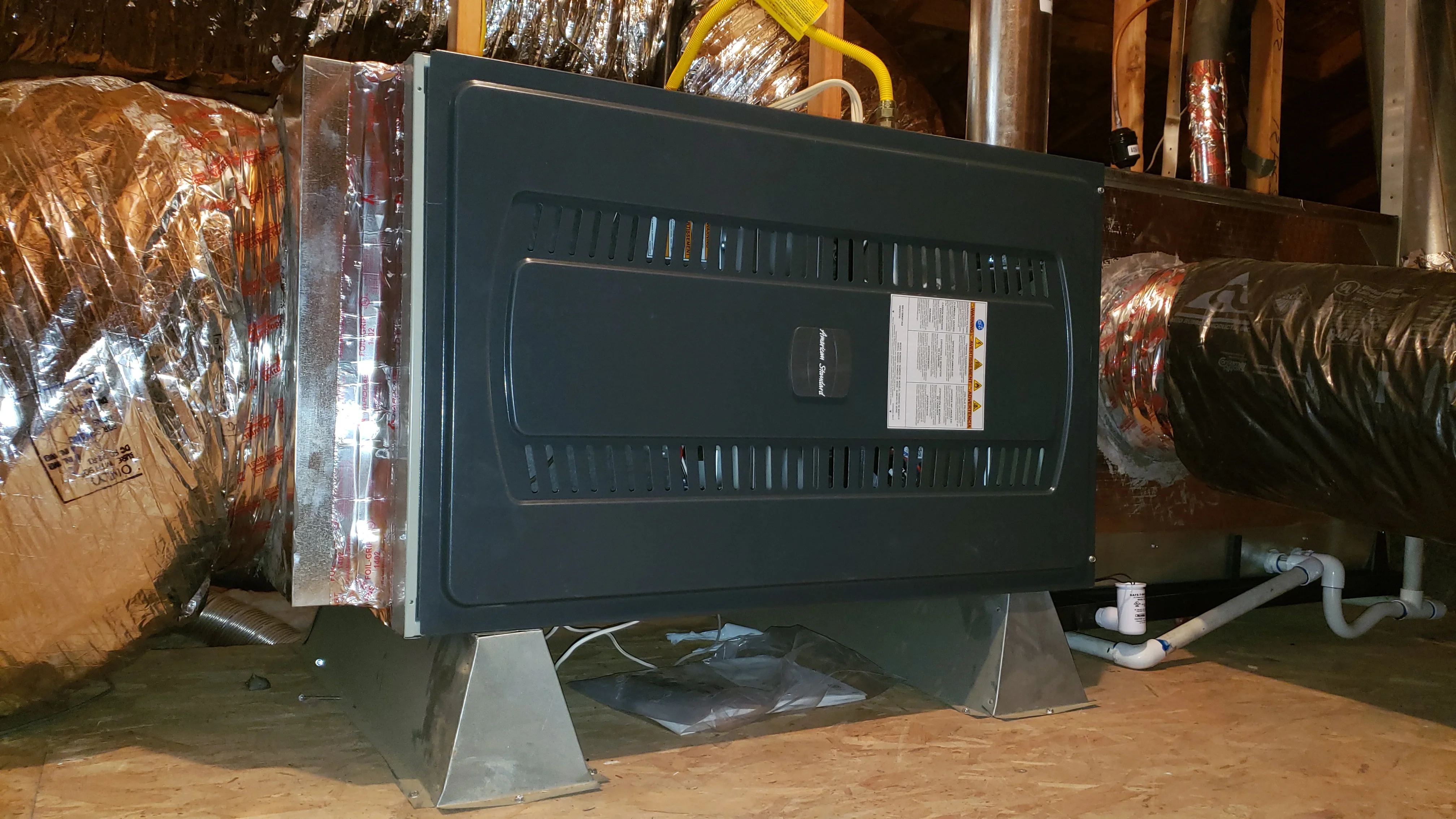 Installed furnace unit with insulated ductwork and PVC drain lines in mechanical room