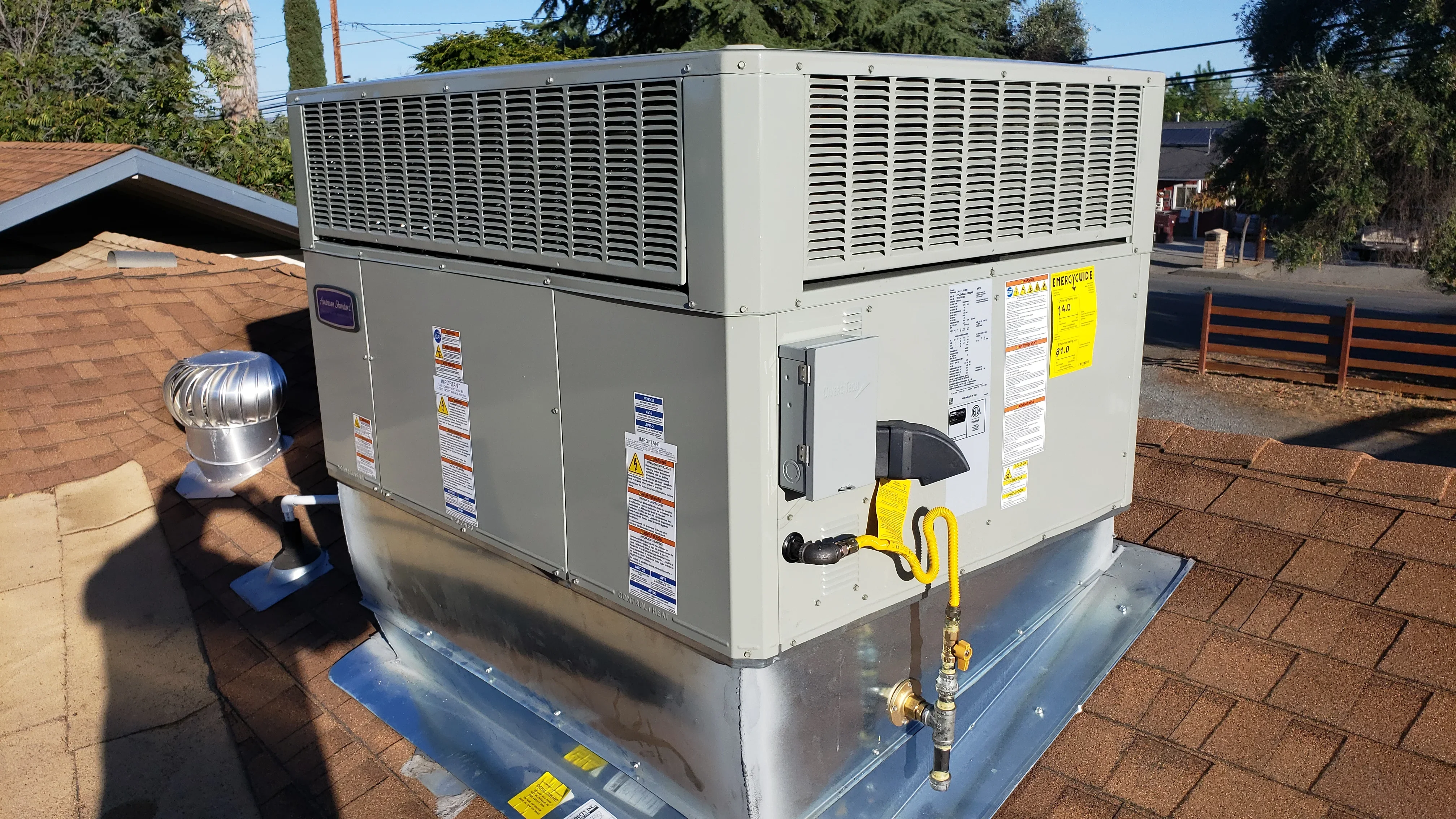 New rooftop HVAC unit with dual sections and yellow safety connections installed on residential roof