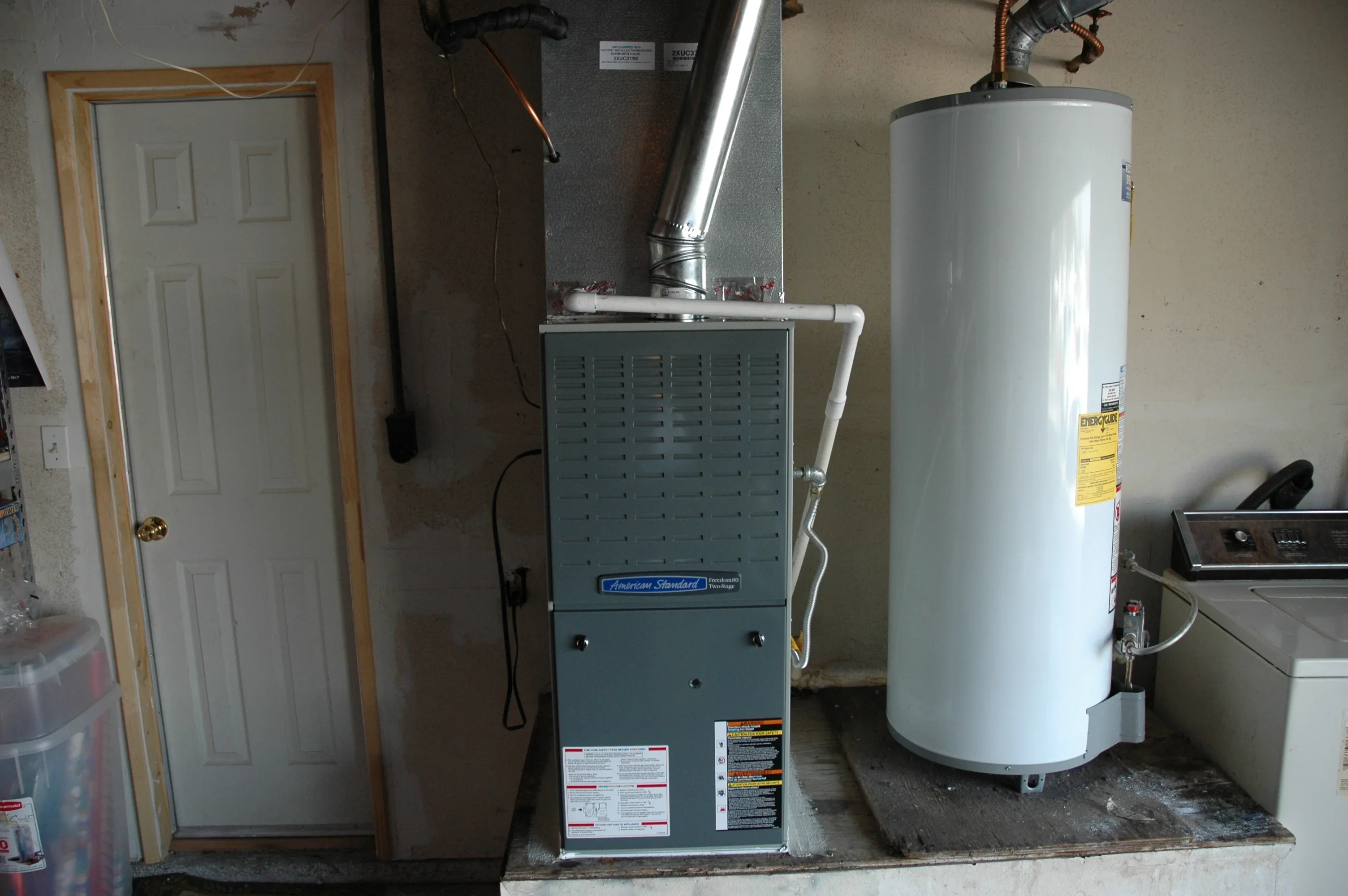 Newly installed American Standard furnace and white cylindrical water heater in utility room